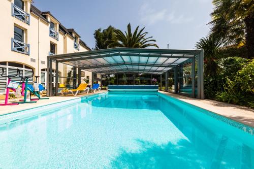 a large swimming pool with a canopy over it at Hotel Aigue Marine in Tréguier