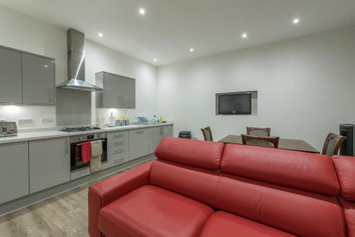 a living room with a red couch and a kitchen at Haymarket Spacious 3 Bedroom Street Level in Edinburgh