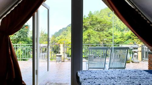a bedroom with a bed and two chairs looking out a window at Bedugul Lake View Residence Unit A-1 in Bedugul