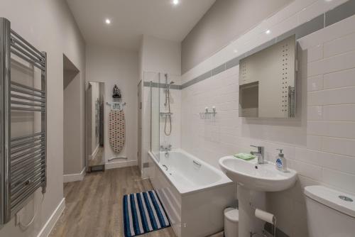 a white bathroom with a sink and a bath tub at Haymarket Spacious 3 Bedroom Street Level in Edinburgh