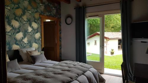 a bedroom with a bed and a sliding glass door at Maison d hotes Lapitxuri in Arcangues