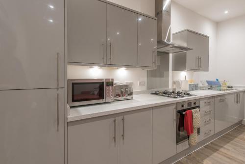 a kitchen with white cabinets and a microwave at Haymarket Spacious 3 Bedroom Street Level in Edinburgh
