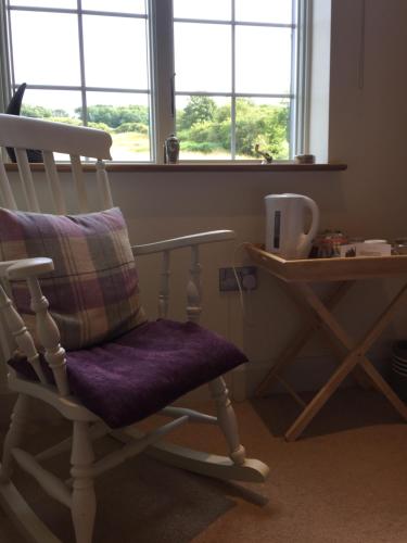 a rocking chair in a room with a desk and windows at Martlets B&B in Shanklin
