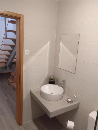 a white bathroom with a sink and a staircase at Casa do Califórnia in Ribeira Grande