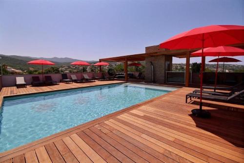 una piscina con sombrillas rojas en una terraza en Residence ACQUA LINDA Porticcio, en Porticcio