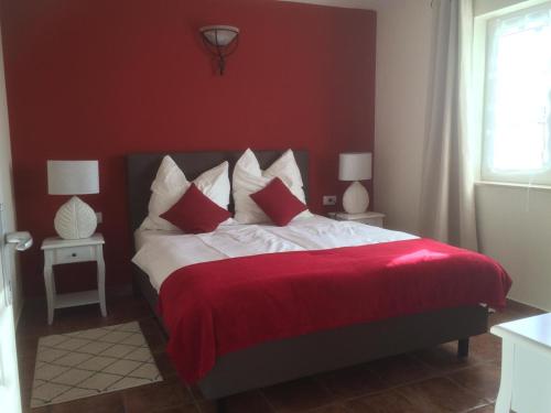 czerwona sypialnia z łóżkiem z czerwoną pościelą i poduszkami w obiekcie Antonio Solimar Apartments w Poreču