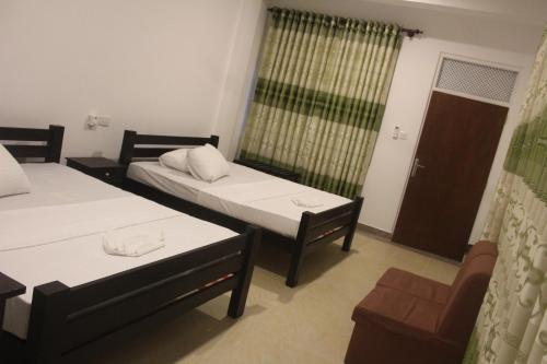 a room with two beds and a chair and a window at Hotel Senora in Kataragama
