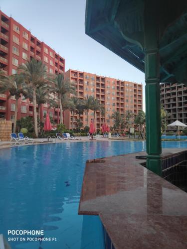 a large swimming pool with palm trees and buildings at Aِِِpartments Golf Porto Marina Aqua View (Families Only) in El Alamein