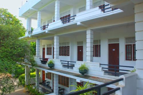a white building with red doors and potted plants at Hotel Senora in Kataragama