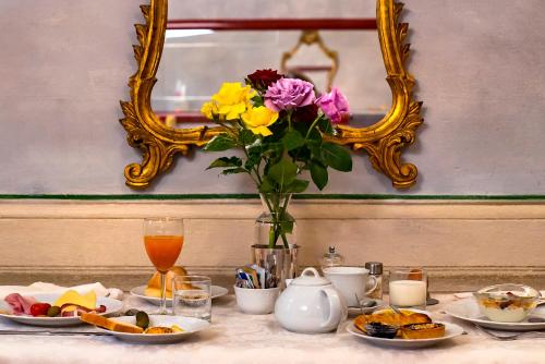 a table with plates of food and a vase of flowers at Torre dei Lari Residenza d'Epoca in Florence