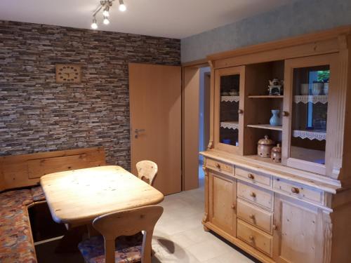 a dining room with a wooden table and a brick wall at Ferienwohnung am Sorpesee in Allendorf