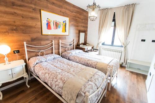 two beds in a bedroom with wooden walls and wooden floors at Relais Garibaldi in Avezzano