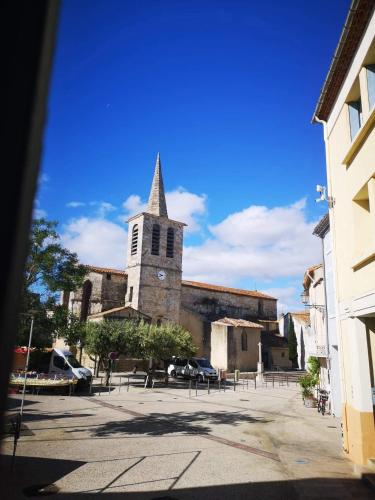 une église avec une cloche et des voitures garées dans un parking dans l'établissement Maison de village avec sa charmante grand chambre avec balcon, à Fleury