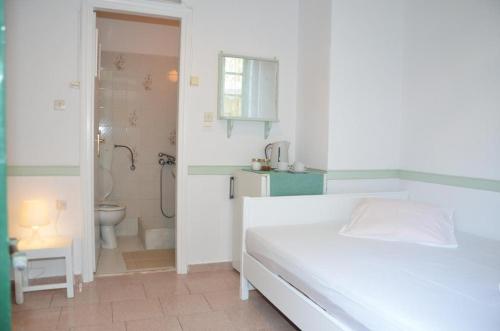 a white bedroom with a white bed and a bathroom at Aegli Rooms in Tinos