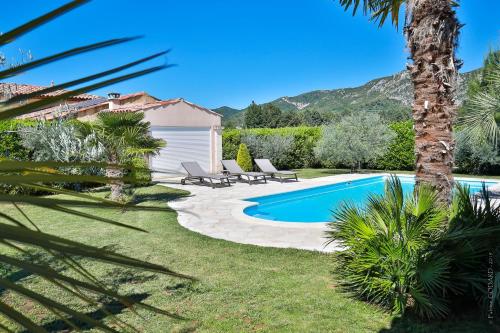 a pool in a yard with two chairs and a house at Gîte "Les Farigoules" in Villeneuve