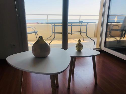 Deux tables avec des vases sur elles devant une fenêtre dans l'établissement Superbe appartement 3 étoiles Ajaccio début Sanguinaires, à Ajaccio