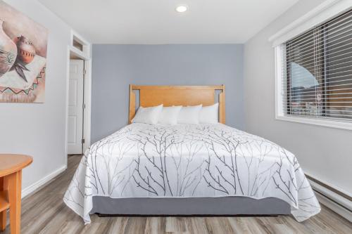a bedroom with a bed with a white comforter and a window at Westridge Motor Inn in Osoyoos