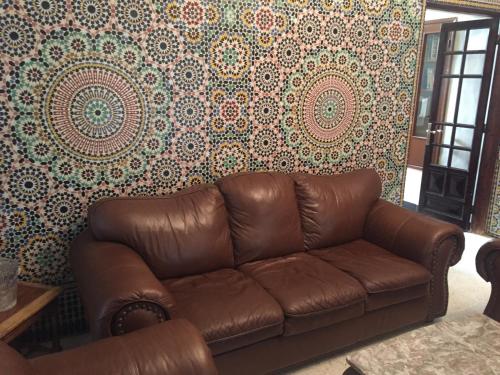 a brown leather couch in a living room with wallpaper at Villa Tazi in Meknès