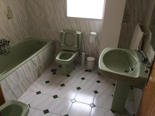 uma casa de banho com um lavatório verde, um WC e uma banheira em Chalet con barbacoa, chimenea y piscina en Alhaurín de la Torre em Alhaurín de la Torre