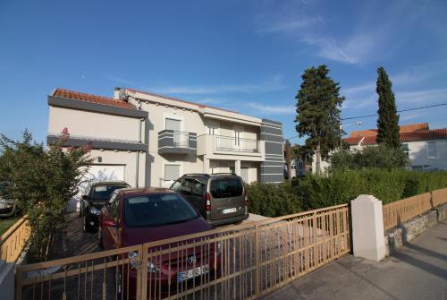 two cars parked in a parking lot in front of a house at Apartments Luna in Sveti Filip i Jakov