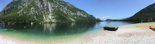 a boat sitting on a beach next to a mountain at Pr`Mružo apartmaji in Bohinj