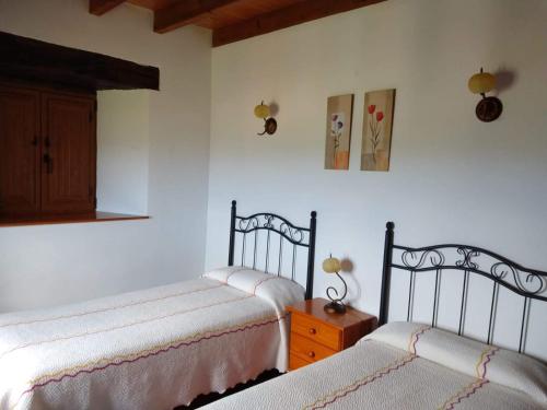 SolórzanoにあるLa Casa del Acebalのベッドルーム1室(ベッド2台、木製キャビネット付)