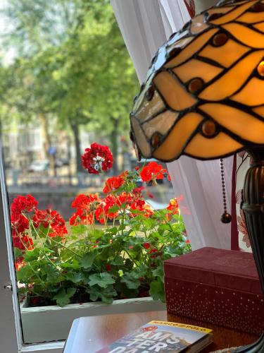 a butterfly sitting on a window sill next to red flowers at Keizershouse Amsterdam in Amsterdam