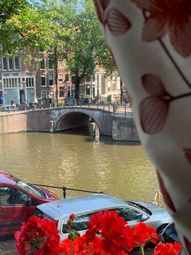a river with cars parked next to a bridge at Keizershouse Amsterdam in Amsterdam