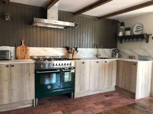 a kitchen with wooden cabinets and a stove at Cuckoostone Barn in Buxton