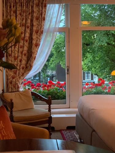 a room with a window with a couch and flowers at Keizershouse Amsterdam in Amsterdam