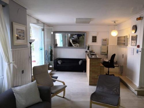 a living room with a couch and chairs and a kitchen at Hotel Rania in Loutra Edipsou