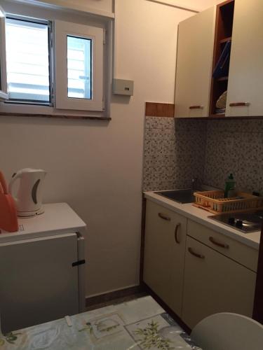 a kitchen with white cabinets and a sink and a window at Apartmani Atila Damir in Omiš
