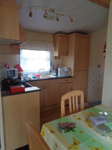 une cuisine avec une table et une cuisine avec une table et des chaises dans l'établissement Mobil-Home Corinne Rastel -le Domaine de Dugny, à Onzain
