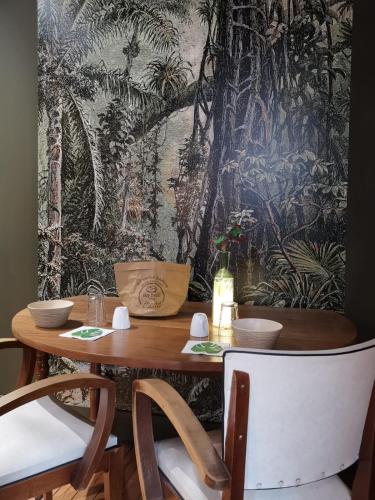une salle à manger avec une table, des chaises et une fresque murale. dans l'établissement La Maison Saint Louis, à Cholet
