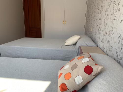 a bedroom with two beds and a pillow on the bed at Apartamento privado a 15 minutos de Santiago y 15 de las playas de Noia y Barbanza in Rois