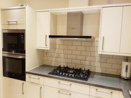 uma cozinha com armários brancos e um forno com placa de fogão em London Luxury Apartments 1min walk from Underground, with FREE PARKING FREE WIFI em Londres