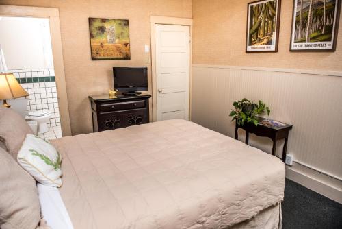 a small bedroom with a bed and a television at Jonquil Motel in Bisbee