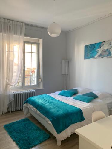 ein weißes Schlafzimmer mit einem großen Bett mit blauen Kissen in der Unterkunft Relais Vacances à la Mer in Berck-sur-Mer