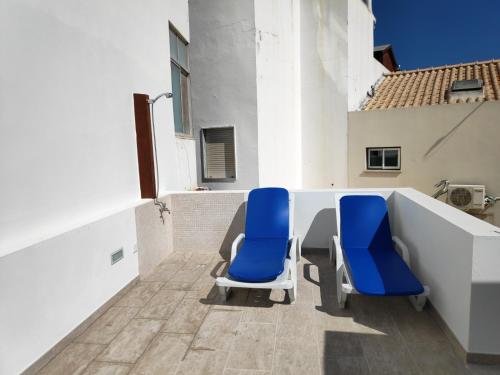 twee blauwe stoelen op het balkon van een gebouw bij The Old Town House by Freetimealgarve in Faro