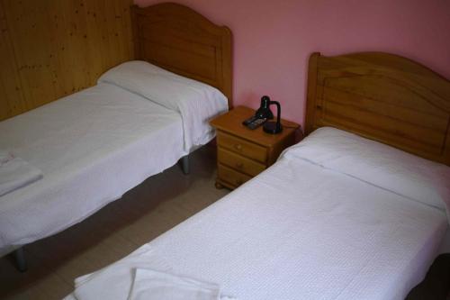 a bedroom with two beds and a telephone on a night stand at Hostal El Alba in Brunete