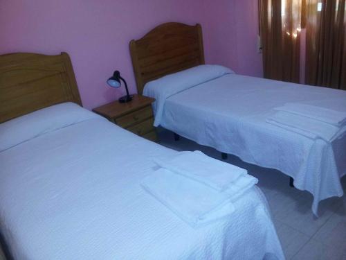 two beds in a hotel room with white sheets at Hostal El Alba in Brunete