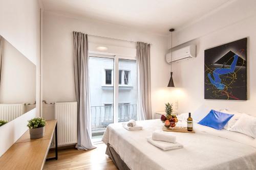 ein weißes Schlafzimmer mit einem großen Bett und einem Fenster in der Unterkunft Kolonaki Square Executive Apartment in Athen