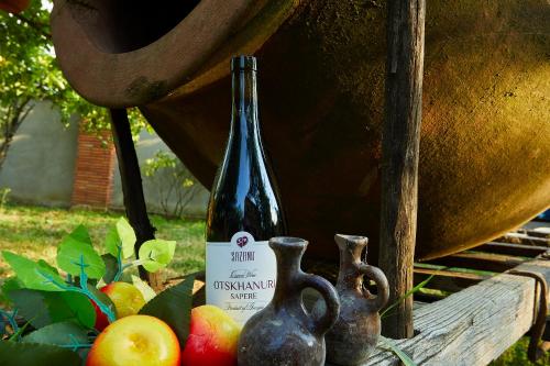 a bottle of wine sitting next to some apples at Ethno Sazano Hotel in Sazano