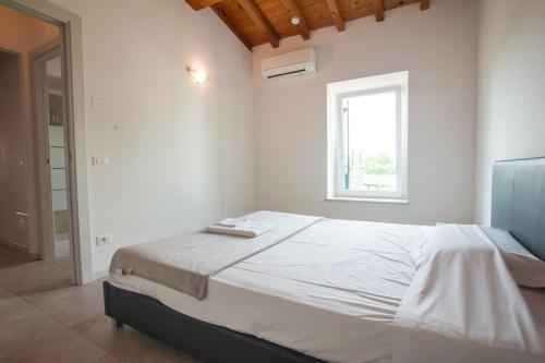 a white bedroom with a large bed with a window at Gate To Verona in Verona