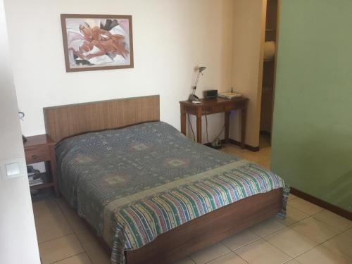 um pequeno quarto com uma cama e uma mesa de cabeceira em Résidence les cactus em Noumea