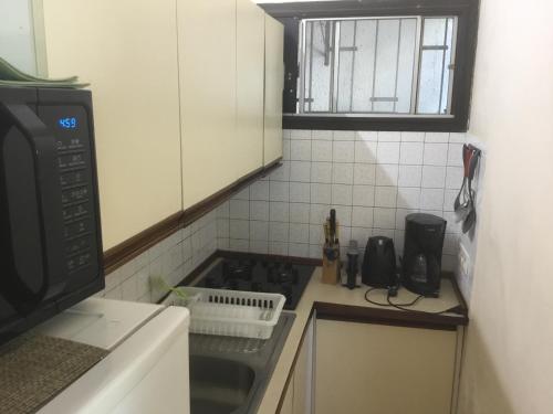 eine kleine Küche mit einem Herd und einer Mikrowelle in der Unterkunft Résidence les cactus in Noumea