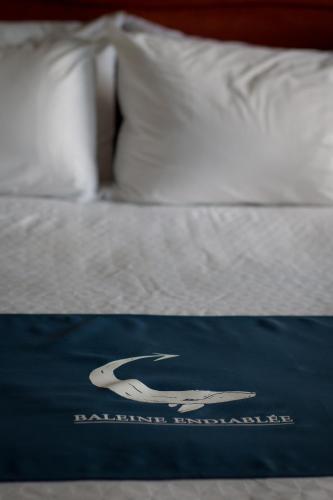 a bed with a blue welcome mat on it at La Baleine Endiablée Microbrasserie in Rivière-Ouelle