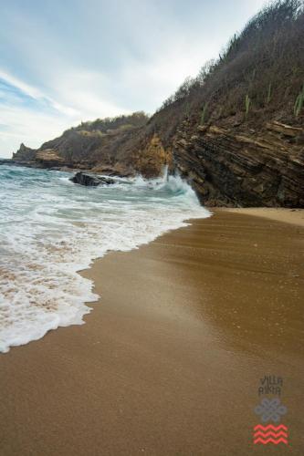a sandy beach with waves crashing on the shore at Villa Aikia (Adults Suites A/C) in Zipolite