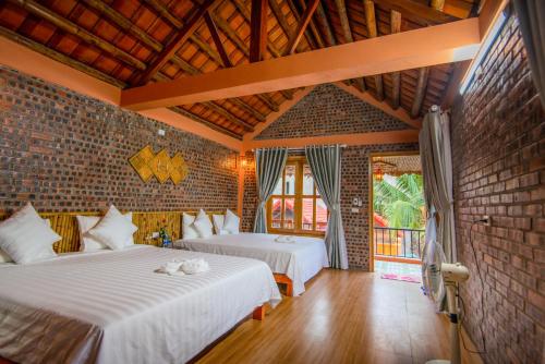 a bedroom with two beds and a brick wall at Tam Coc Summer Bungalow in Ninh Binh
