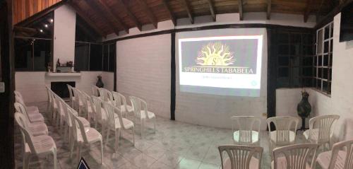 a stage with white chairs and a projection screen at Springhills Quito Airport in Tababela